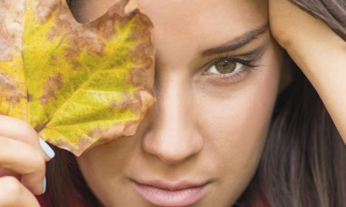 Photo of a woman holding up a leaf to her face