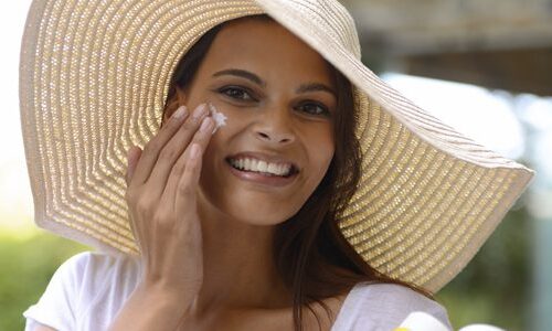 Photo of a woman applying sunscreen to her face