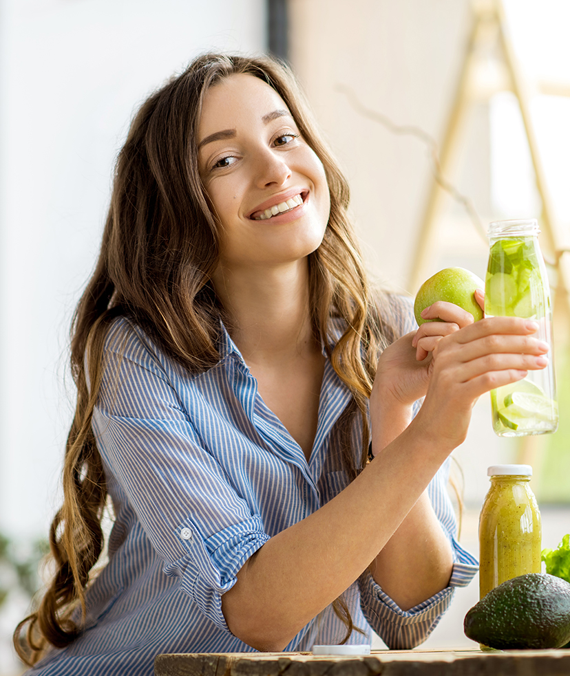 Photo of a woman holding an apple and a bottle of water