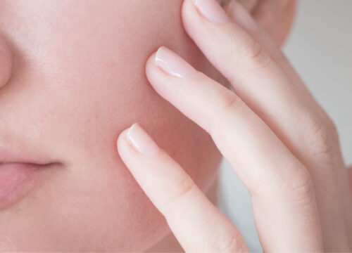 Photo of a woman's lower face and her hand touching her cheek