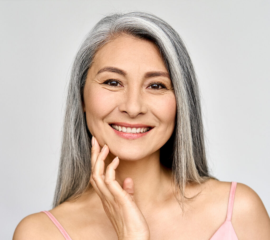 Photo of a happy older woman with great skin, wearing a pink top