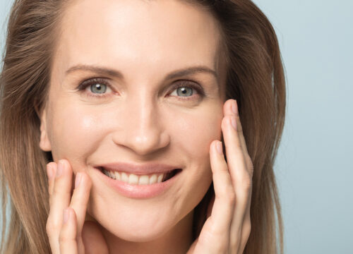 Photo of a smiling woman in her 40s, touching her face