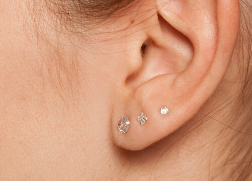 Photo of a woman's pierced ear with multiple diamond earrings