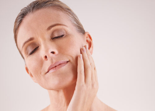Photo of a middle-age woman with great skin touching the side of her face