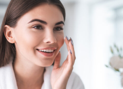 Photo of a happy woman looking at her skin in the mirror