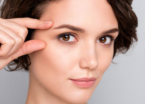 Photo of a woman touching the skin on the outside of her right eye